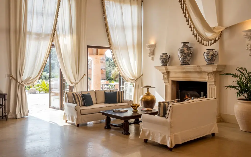 a Mediterranean living room with extra long curtains creating a grand luxury hotel look